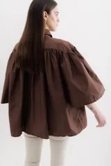 Camisa celeste de algodón con corte amplio, cuello camisero y mangas largas con puños abullonados.