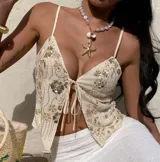 Top de breteles finos color crema, con escote en V, estampado floral con lentejuelas doradas y cierre frontal con lazo.