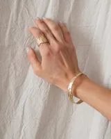 Brazalete rígido dorado con textura irregular.