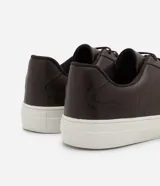 Championes casuales de cuero color marrón oscuro con cordones y suela blanca.