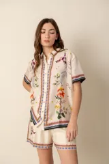 Camisa de seda color crema con estampado floral y de aves, de corte recto, manga corta y cuello camisero.