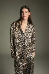 Pijama de dos piezas con estampado animal print de leopardo, compuesto por una camisa de manga larga con cuello clásico y un pantalón largo con cintura elástica.