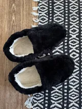 Pantuflas cerradas de cuero lanar color negro con interior de lana color crema.