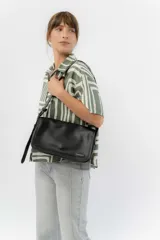 Bandolera moderna de eco cuero texturado color negro, con solapa frontal con cierre magnético oculto y correa regulable para llevar al hombro o cruzada.