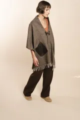Chal de lana fina sin teñir, con calce en hombros, abrochadura con alamar de fieltro, bolsillos de cuero y terminación con flecos. Diseño exclusivo de Don Baez, hecho en Uruguay.