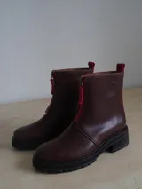 Botas de cuero color borgoña con suela track y cremallera frontal roja.