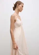 Vestido largo color rosa pálido con tirantes finos y escote en V. Tiene detalle de abalorios y cierre de lazo en la espalda.