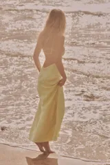 Vestido midi amarillo de satén con escote en V, tirantes finos ajustables y espalda con tiras cruzadas.