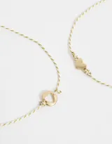 Set de dos pulseras flexibles doradas con dije de corazón y arandela de metal.