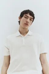 Remera polo blanca de piqué de algodón, corte regular fit, con cuello clásico, tapeta de botones, mangas cortas, remate acanalado en cuello y mangas, y bajo recto con aberturas laterales.