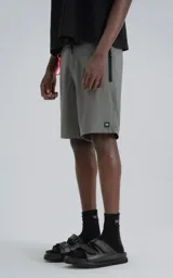 Short de baño gris oscuro, confeccionado en microfibra de secado rápido. Presenta cierre frontal con velcro y cordón, y tres bolsillos con cierre (dos laterales y uno trasero).