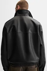 Cazadora negra relaxed fit confeccionada en tejido efecto piel. Tiene cuello solapa, manga larga con puño abotonado, bolsillos de vivo en cadera, bolsillo interior, bajo con elástico y cierre frontal de cremallera.