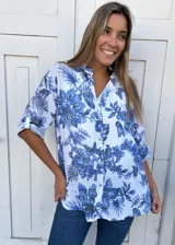 Camisa blanca con estampado floral en tonos azules, cuello mao y mangas 3/4 con botón.