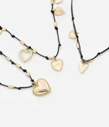 Set de tres collares de hilo encerado negro con dijes de corazones dorados de diferentes estilos.