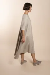 Vestido largo debajo de la rodilla, acampanado, color marrón, con cuello bote, bolsillos laterales y mangas 3/4 con detalle de tajo.