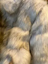 Chaqueta corta de piel sintética color gris con cuello alto y cierre metálico.