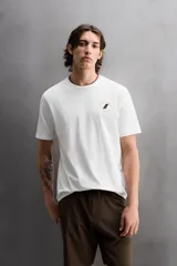 Camiseta blanca de corte holgado confeccionada en tejido de algodón con elasticidad. Tiene cuello redondo, manga corta y estampado en el frente con el logo de la marca y un diseño de tablas de surf.