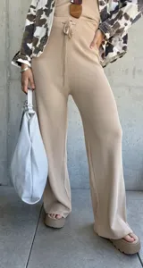 Pantalón de punto color beige, de corte ancho y tiro alto, con cintura elástica y cordón ajustable.