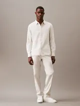 Camisa de manga larga color blanco hueso, confeccionada en lino y algodón. Tiene cuello clásico, cierre con botones y un bolsillo en el pecho.