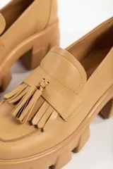 Mocasines negros de cuero con suela track y detalle de borlas.