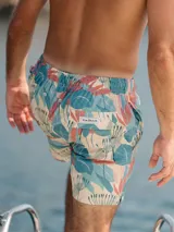 Short de baño para hombre con estampado de hojas en tonos celeste, verde, beige y coral. Tiene elástico en la cintura, tres bolsillos (dos laterales y uno trasero), tela con 10% spandex de secado rápido con doble costura de seguridad e interior con mesh hipoalergénico.