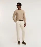 Pantalón de hombre color crudo, confeccionado en sarga de algodón y elastano. Diseño clásico con cintura fija, trabillas, cierre con cremallera y botón, y bolsillos.