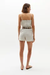 Short de lino 100% orgánico color natural, de cintura alta con tablas que le dan un calce holgado. Posee bolsillos laterales y cierre frontal con gancho metálico.