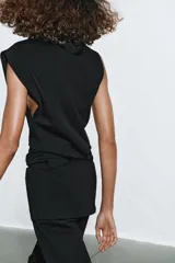 Top de algodón color beige, con cuello recto, mangas asimétricas y detalle de tejido drapeado en el lateral.