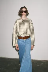 Camiseta de manga larga a rayas horizontales blancas y negras, con cuello redondo y bajo con aberturas laterales.