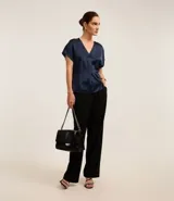 Blusa color café confeccionada en poliéster y elastano, con acabado satinado, escote V y mangas cortas. Presenta pliegues delanteros.