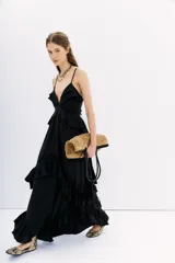 Vestido largo negro con breteles finos, espalda descubierta con tiras de ajuste y volados en escote, cintura y falda.
