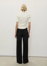 Pantalón de jean negro de corte wideleg, tiro alto, con cierre de cremallera y botón, cinco bolsillos y trabillas.
