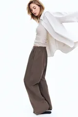 Pantalón marrón de lino, corte holgado, tiro alto, cintura elastizada con cordón ajustable, bolsillos laterales y pierna ancha.