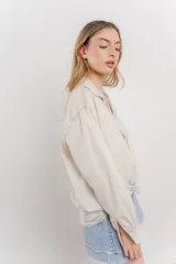Camisa color crema de manga larga con cuello camisero y detalles de encaje en el escote. Se ata en la parte delantera.