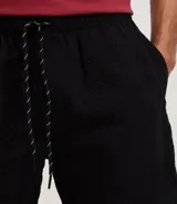 Bermuda de microfibra color beige, con cintura elástica y cordón ajustable. Presenta textura en el tejido y un bolsillo lateral.