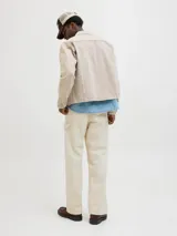 Pantalón jean color crema, corte amplio, con tiro alto, cinco bolsillos y cierre con botones.