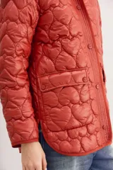 Campera color ladrillo con matelassé de corazones, corte amplio, mangas largas y bolsillos con solapa y botones snap en el frente.