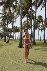 Top de bikini amarillo con textura acanalada, corte triangular, breteles regulables, pieza decorativa de resina verde en el centro y forro interno.