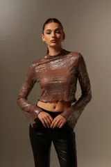 Blusa marrón con brillos plateados, cuello alto y mangas largas acampanadas.