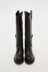 Bota alta de caña ancha color negro, con cierre lateral y detalle de hebilla ajustable en la parte superior de la caña. Suela de goma gruesa con relieve.