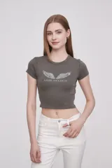 Remera gris de corte crop con cuello redondo y mangas cortas. Estampado frontal con alas y texto "Angel on Earth".