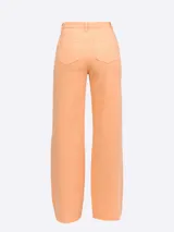 Pantalón de jean tiro alto color naranja claro, de corte ancho (wide leg) y bajo deshilachado. Presenta cinco bolsillos.