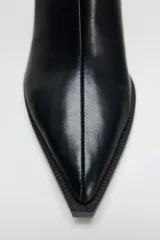 Botín de cuero negro con punta fina, cierre lateral con cremallera y tacón ancho de 6 cm.