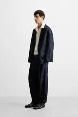 Blazer azul oscuro de denim, corte relaxed fit, con cuello de solapas de muesca, manga larga con puños abotonados, bolsillos de solapa en la cadera, abertura en el centro de la espalda y cierre frontal con botones. Sin forro interior.