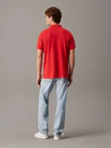 Chomba roja de piqué de algodón, corte regular, cuello clásico, cartera de botones, bajo con aberturas laterales y logo de Calvin Klein bordado en el pecho.