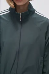 Campera deportiva verde con cierre frontal, cuello alto y tres rayas blancas en las mangas.