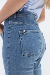 Pantalón de jean de tiro alto, corte recto y largo hasta el tobillo. Presenta bolsillos delanteros con solapa y alforza central.