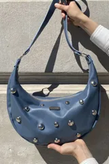 Cartera bandolera color gris topo con apliques de tachas metálicas plateadas.