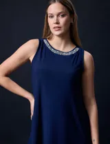Vestido azul marino de seda fría, sin mangas y escote a la base con aplique de perlas.