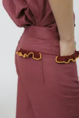 Pantalón de jean azul oscuro, de corte acampanado, con bolsillos delanteros con detalle de volados.